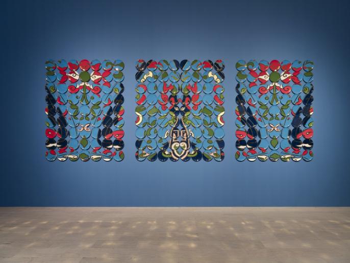 Installation photo of ceramic plates on a blue wall by Molly Hatch