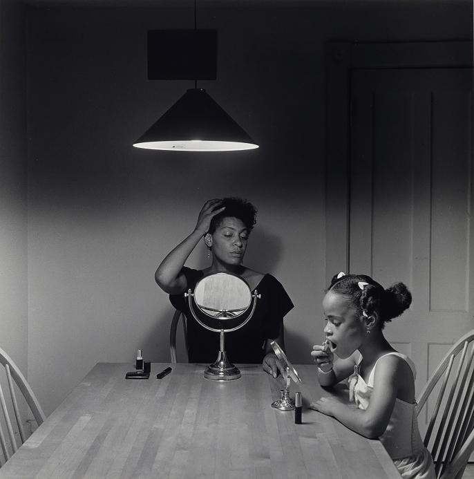 A Black and White photo oh a mother and her daughter at a table, applying makeup