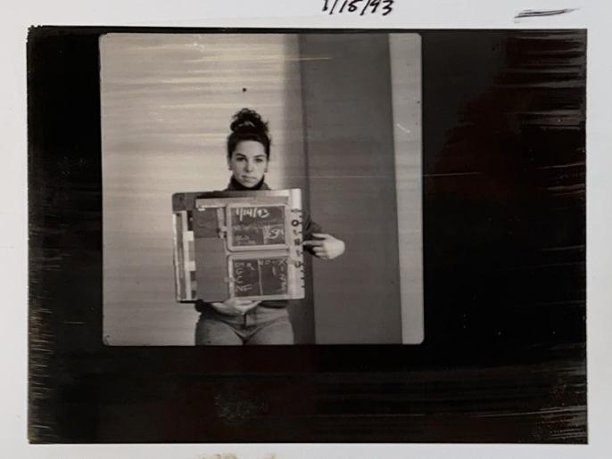Black and white photo of young woman holding test strip on stool