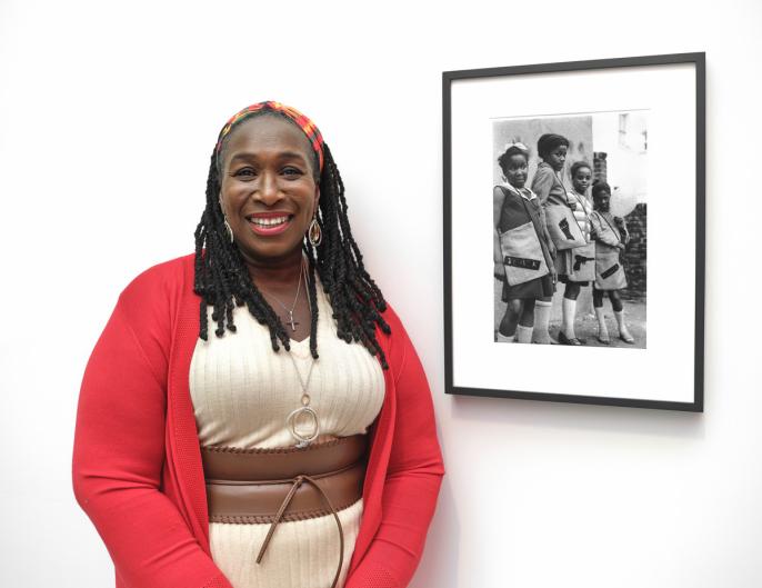 A woman stands in front a framed black-and-white photograph