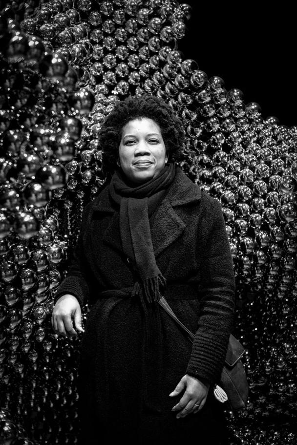 A black and white photo of artist Sharl G. Smith in front of one her beaded sculptures