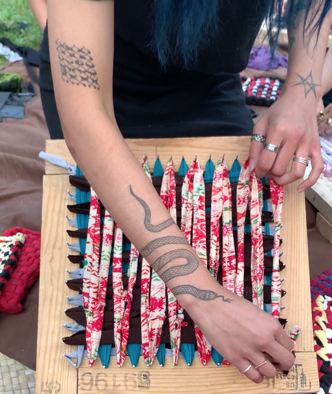 An image of Norwin Anne weaving using the Basahan method. She weaves multi-coloured fabric on a handmade loom