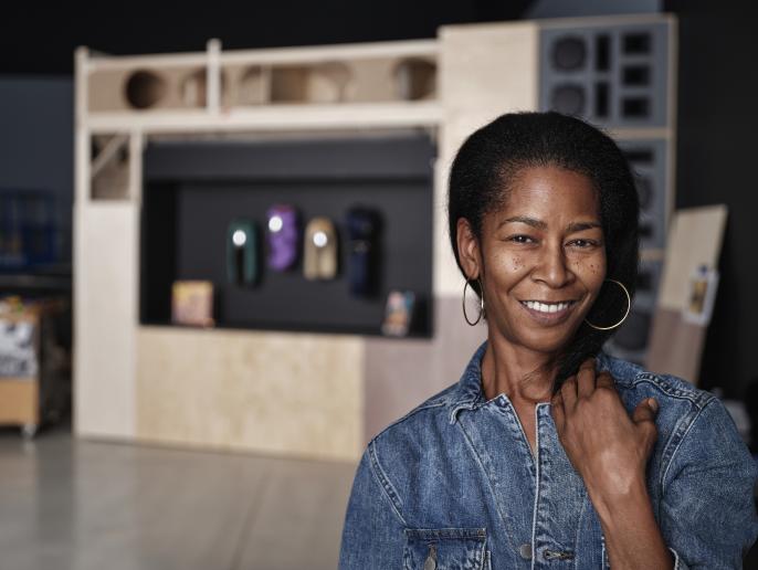 A photo of cosmetologist Dionne Alexander posed in front of her wigs featured in The Culture