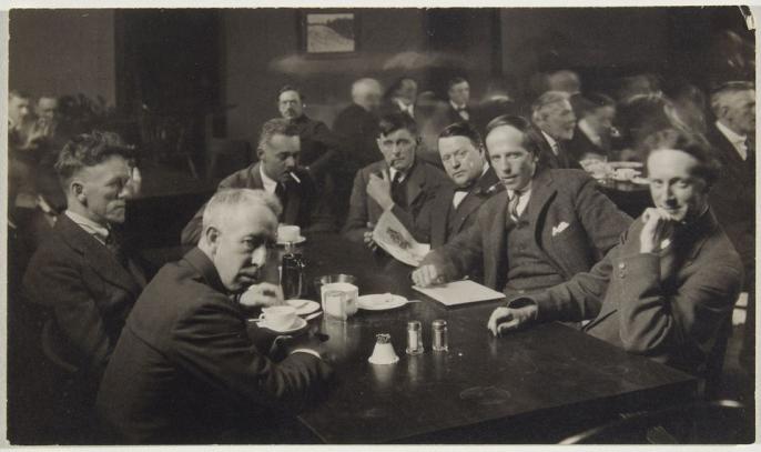 A black and white photograph of members of the Group of Seven seated around a table looking at the camera