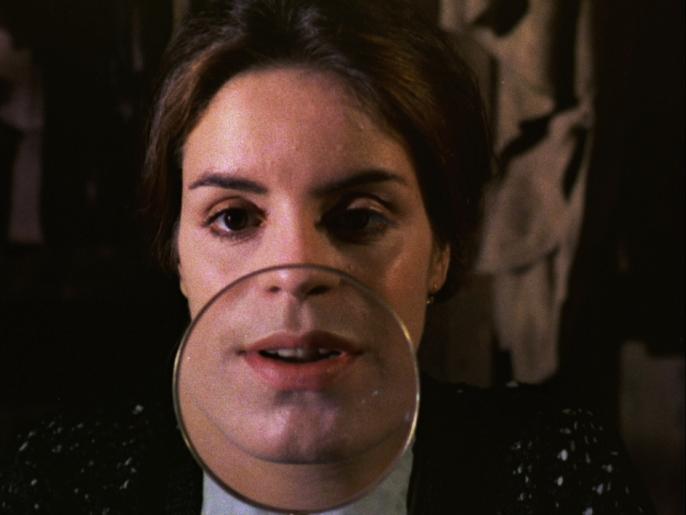 Film still of Joyce Wieland's film The Far Shore showing a woman with a magnifying glass placed in front of her mouth