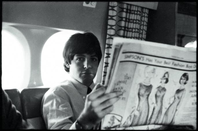A photo of Paul McCartney on a plane reading the Toronto Star Newspaper in 1964