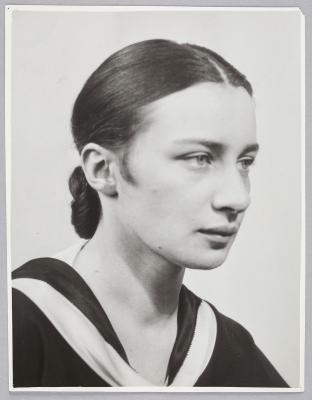 A young woman with her hair in a sleek bun and a neutral facial expression.