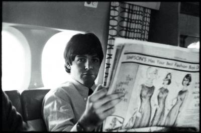 A photo of Paul McCartney on a plane reading the Toronto Star Newspaper in 1964