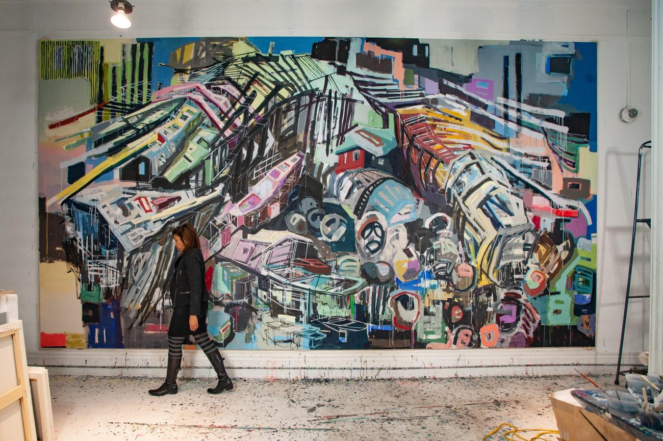 Denyse Thomasos walking in front of her painting Arc