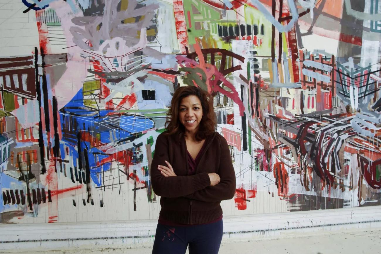 Denyse Thomasos standing in front of her painting Babylon