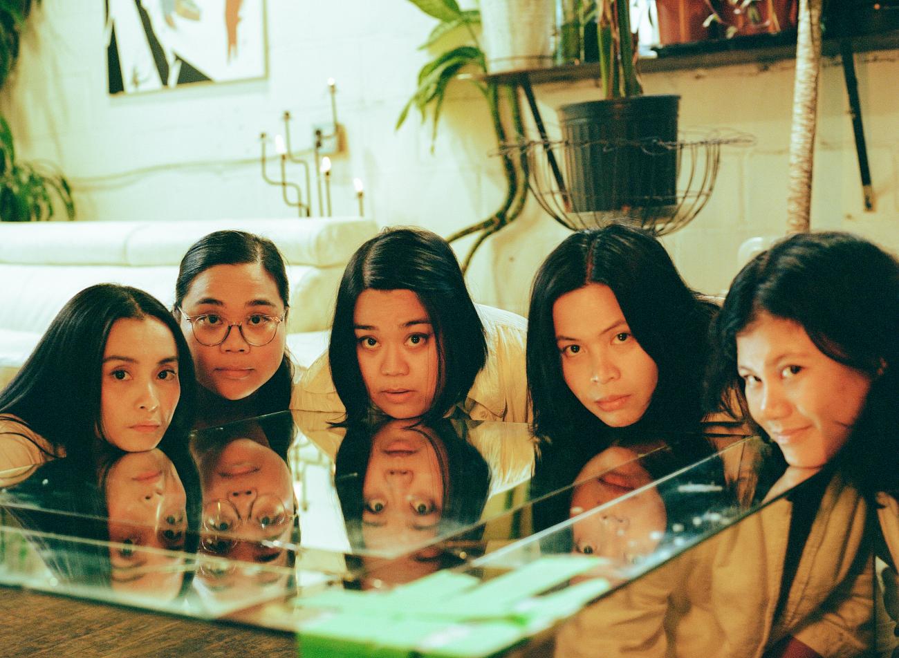 An image of the group Pantayo with their faces resting on a reflective table