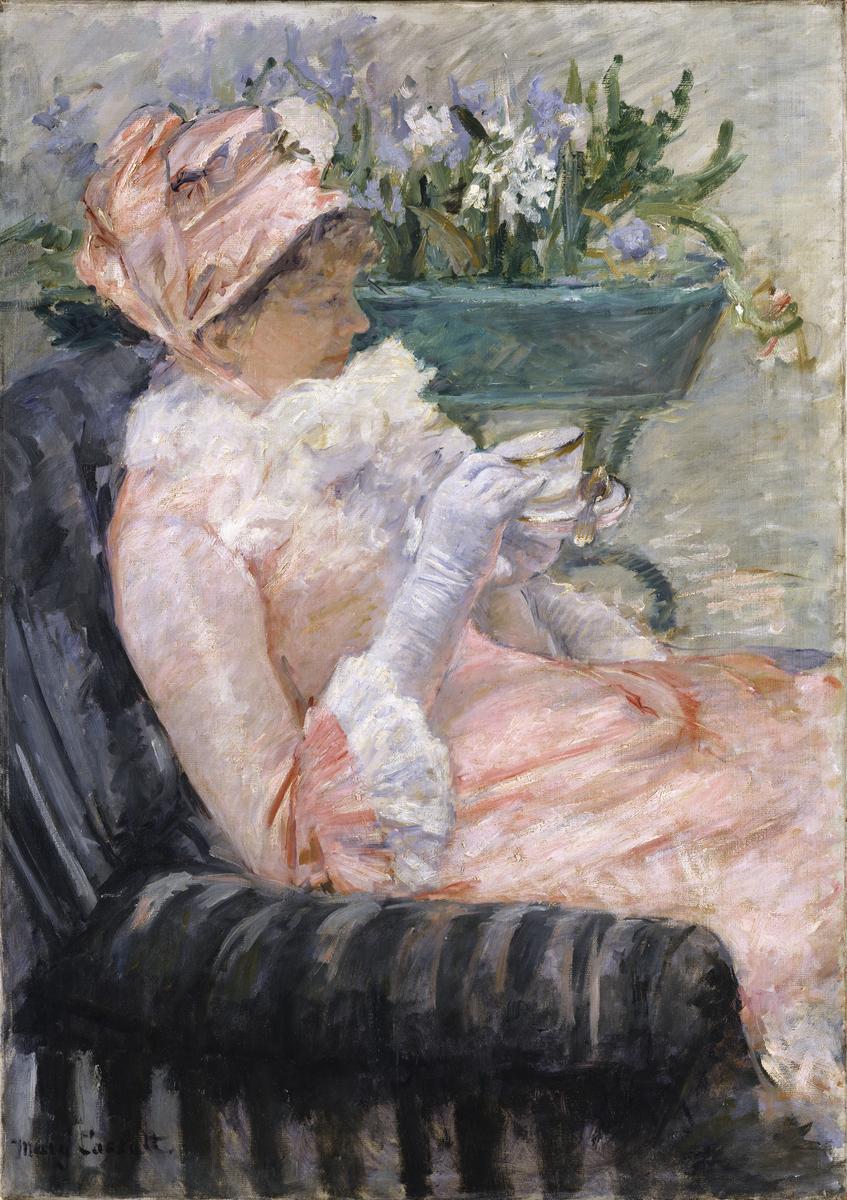 An image of the painting The Cup of Tea by Mary Cassatt, which features a woman in a pink fluffy dress drinking tea on a black striped arm chair with flowers behind her