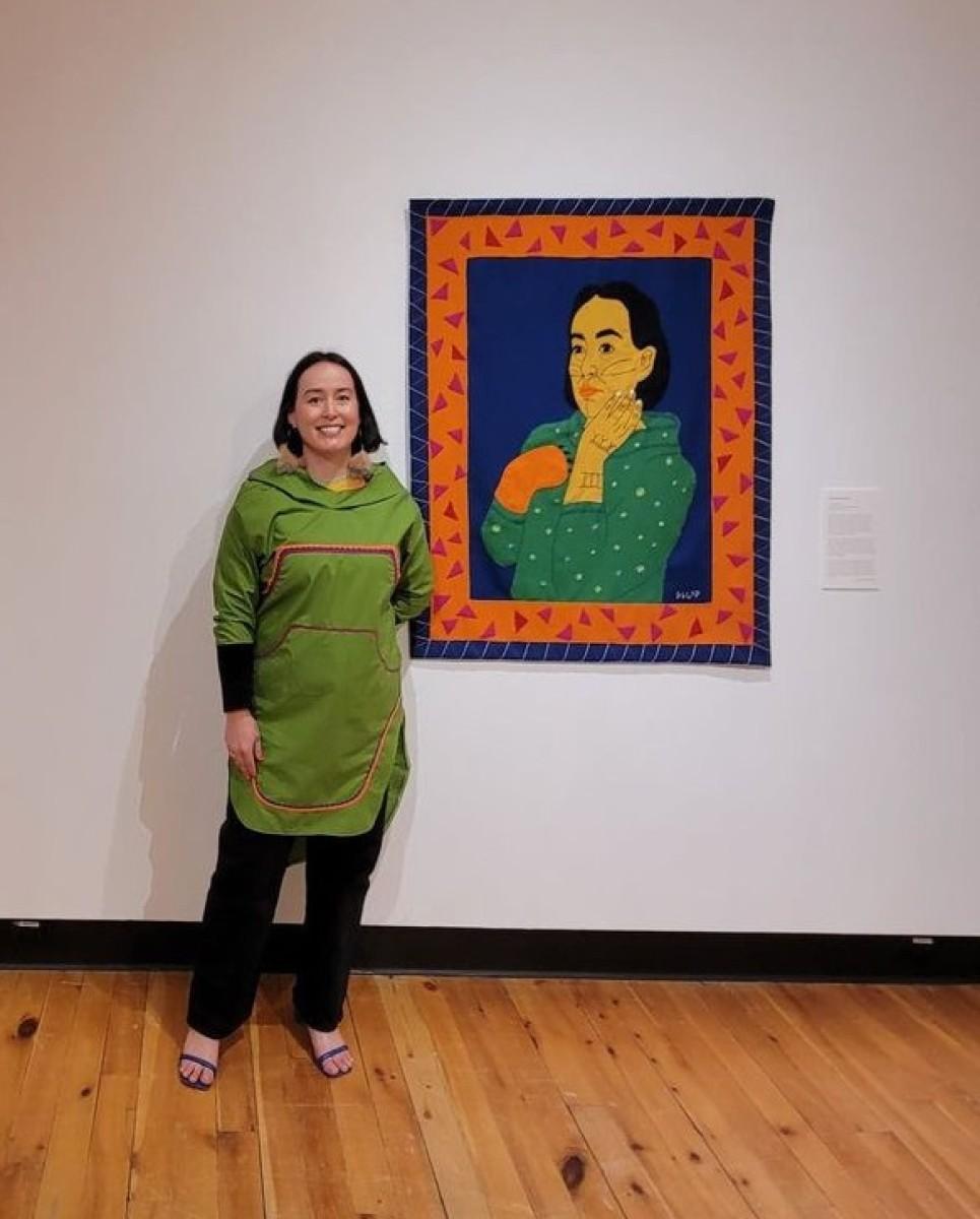 A picture of the artist Gayle Uyagaqi Kabloona standing beside her work Tiriganiaq