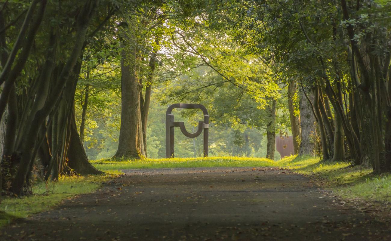 Avenue of trees opening onto monumental bronze sculpture