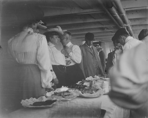 Black and white photo of people dining onboard a ship in 1906