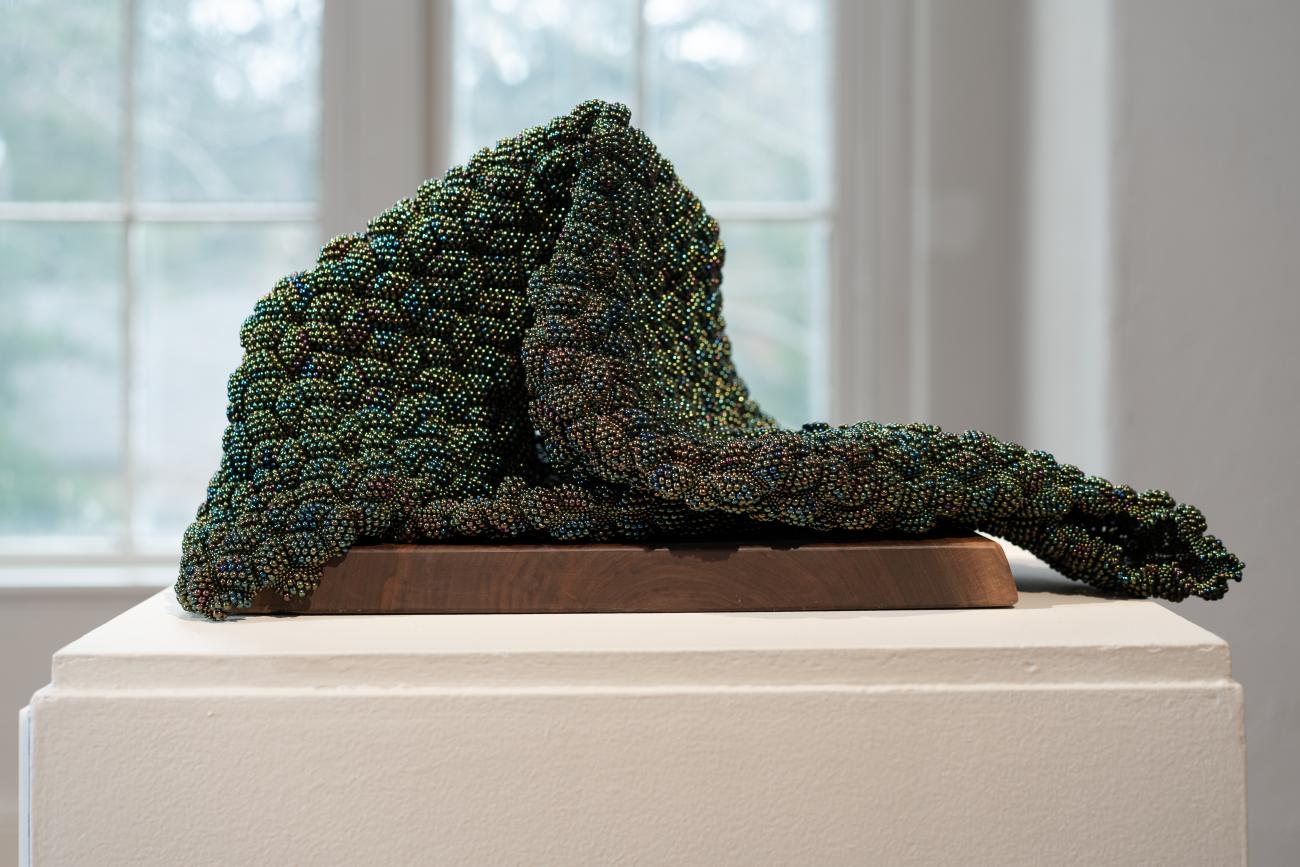 An image of Sharl G. Smith's beaded sculpture Loss. The sculpture uses iridescent green glass beads.