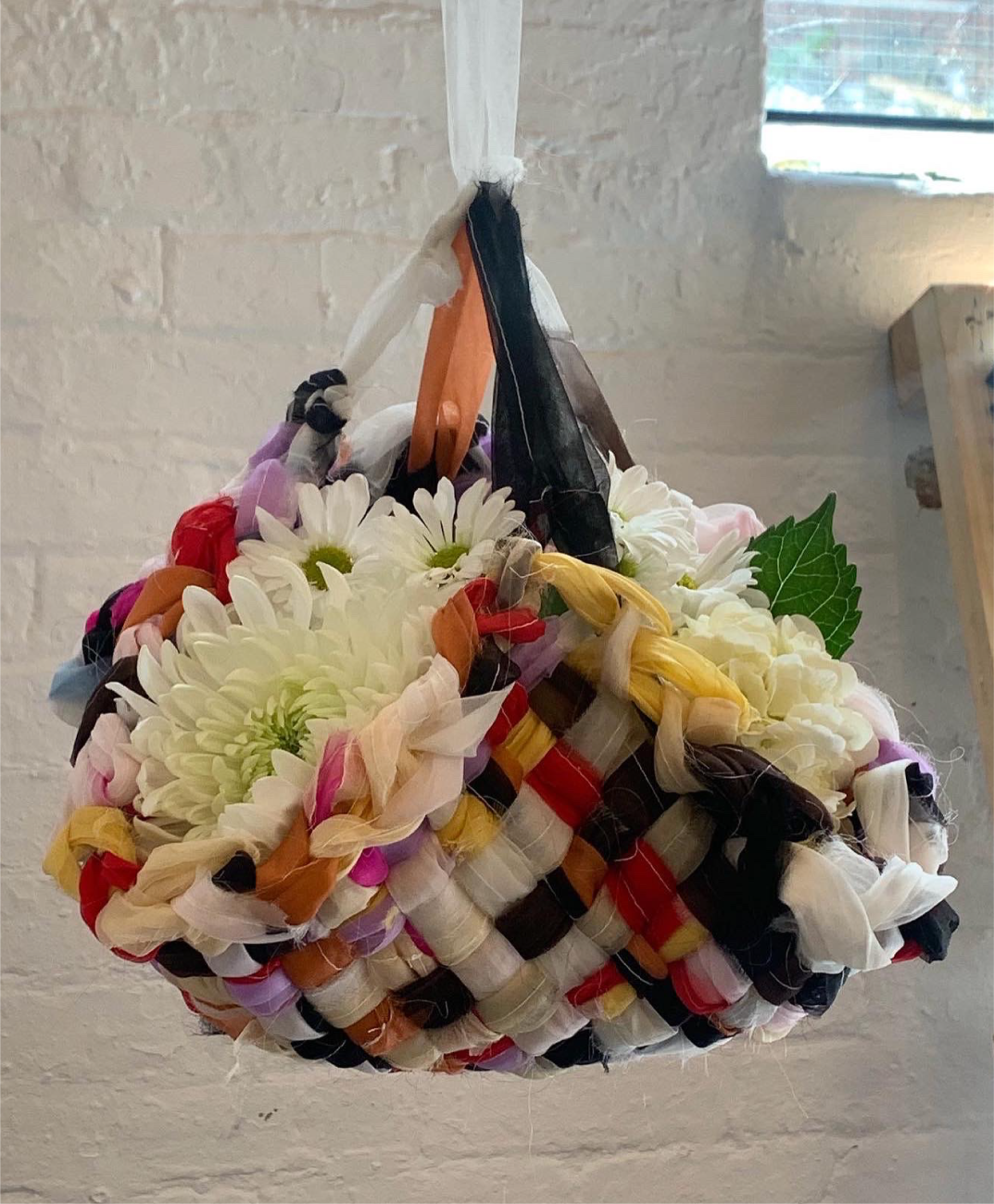 An image of a multi-colour woven basket filled with flowers.