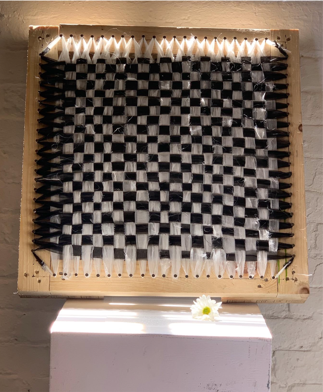 An image of a handmade Bashan loom with a black and white textile woven into it by Norwin Anne