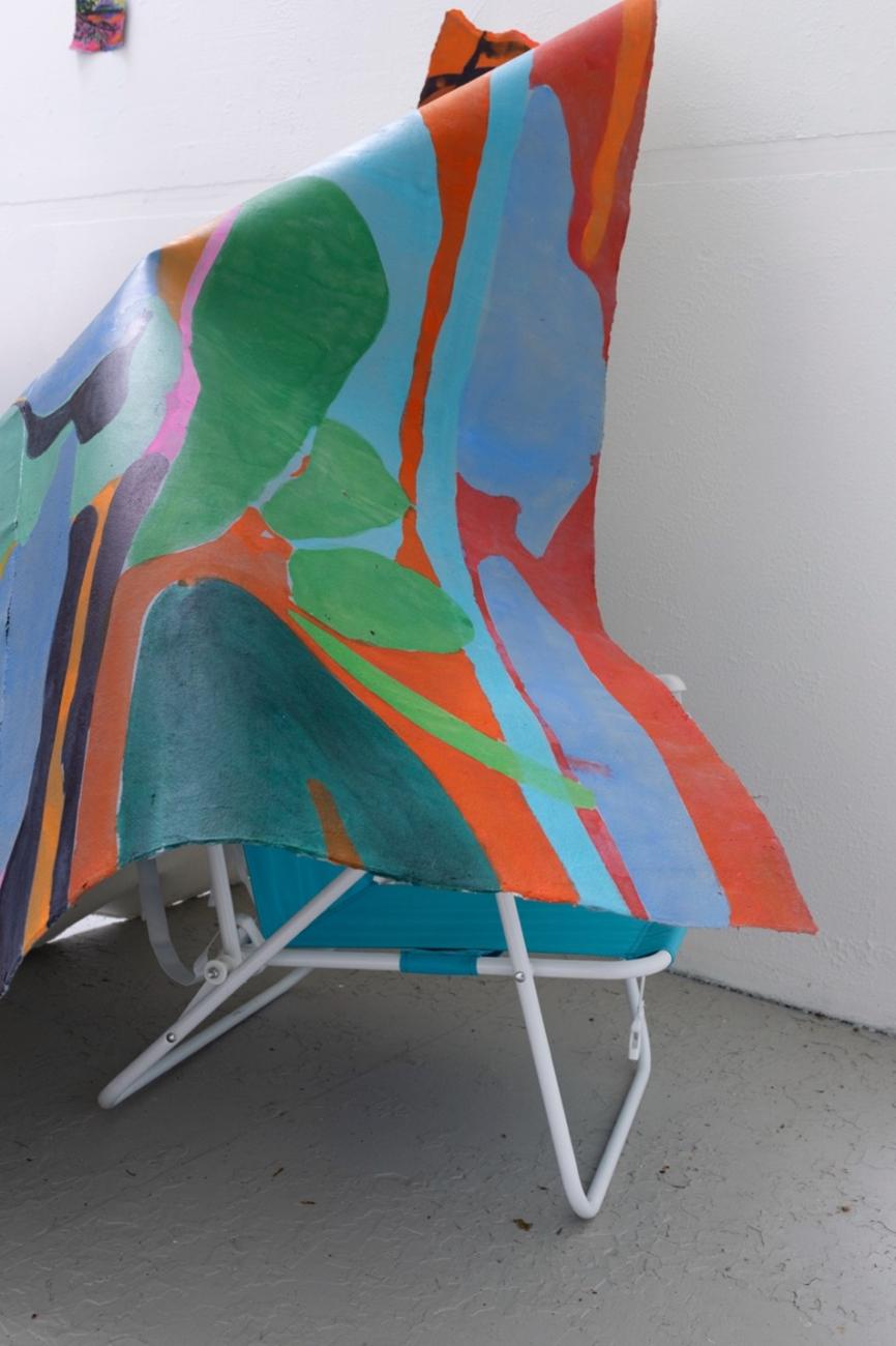 An image of Maru Aponte's work Miss Palomar. The work comes out of the wall and rests on a found beach chair.