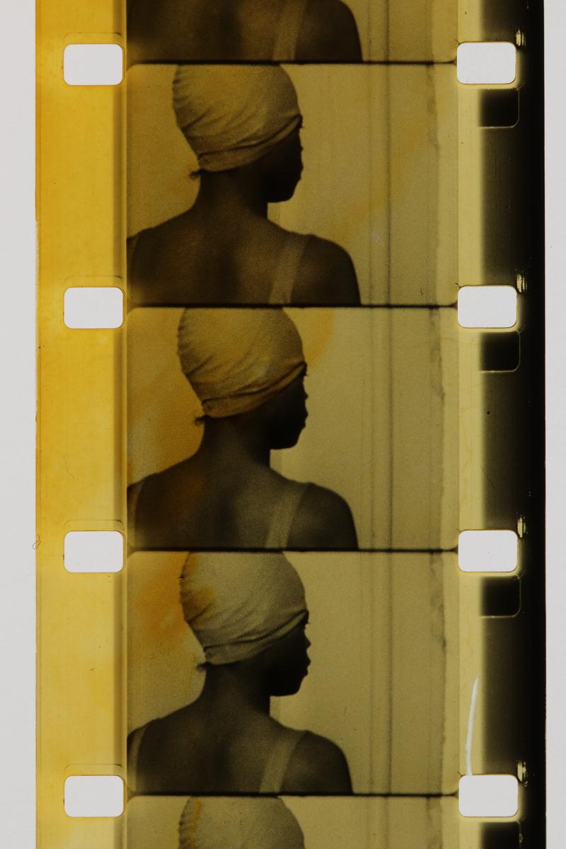An image of a film print from Joyce Wieland's film Handtinting. This film print features a woman with a swim cap on