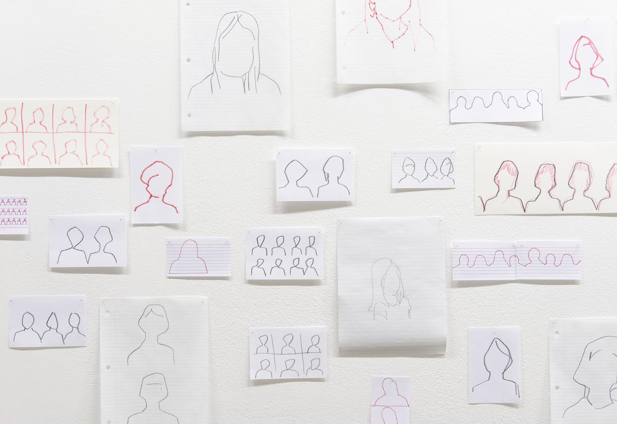 A detail photo of FayeHeavyShield's work I'll know you when I see you, which features silhouettes drawn on different sheets of paper