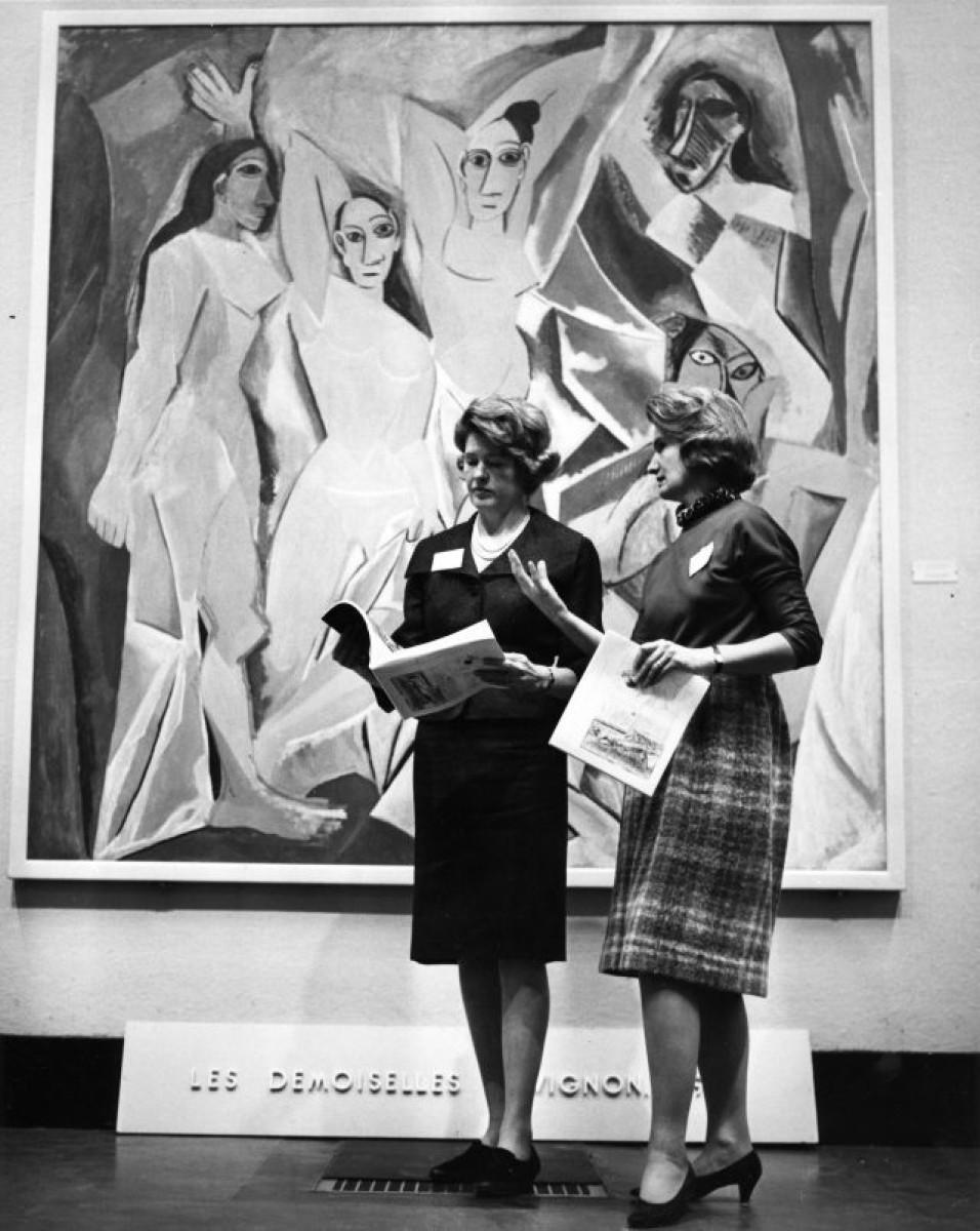 two women standing in front of Picasso painting