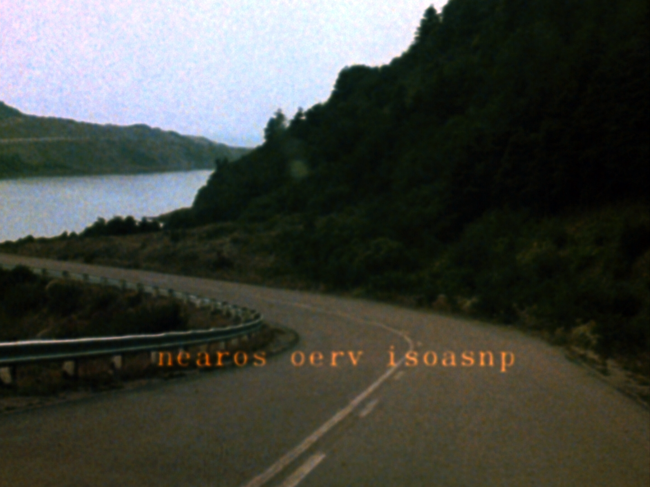 FIlm still from Joyce Wieland's Reason over passion showing a road landscape with the words Reason Over Passion superimposed