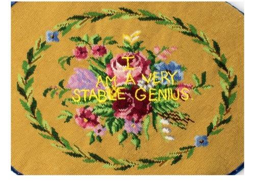 An image of Donald Trump's quote &quot;I am a Very Stable Genius&quot; stitched on top of flowers at the centre of a yellow needlepoint cushion work