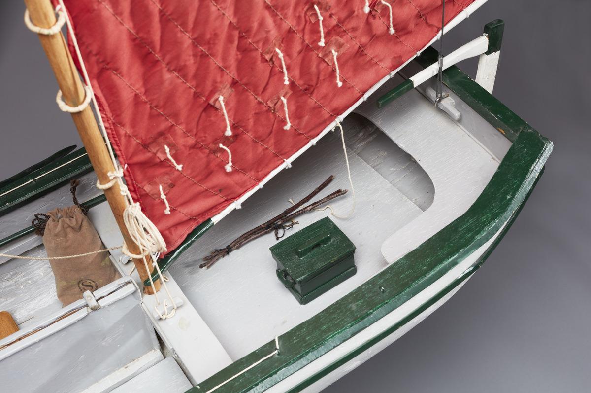 A detail shot of Angus Trudeau's boat model Red Sailboat. It shows fishing lures and a green box inside the boat.