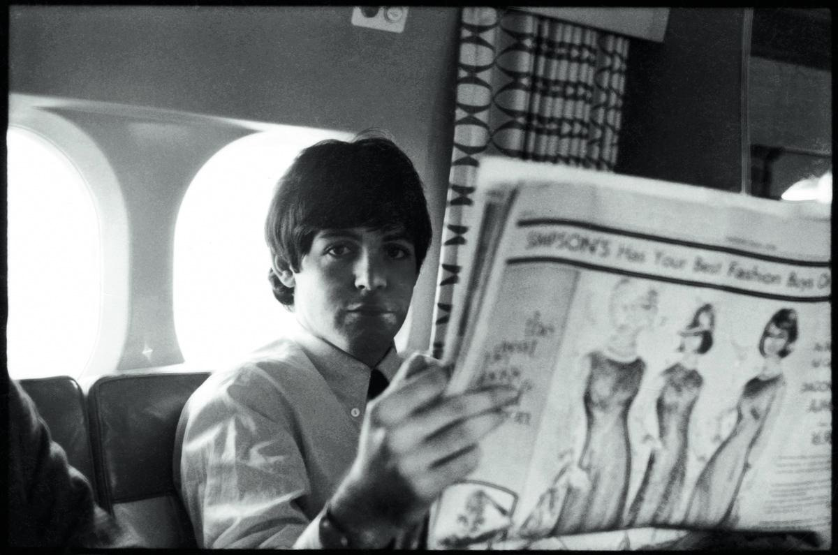 A photo of Paul McCartney on a plane reading the Toronto Star Newspaper in 1964