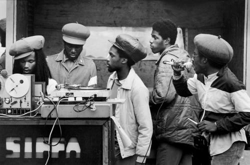 A Black and white photograph of a group of Caribbean- British men gathering a sound system