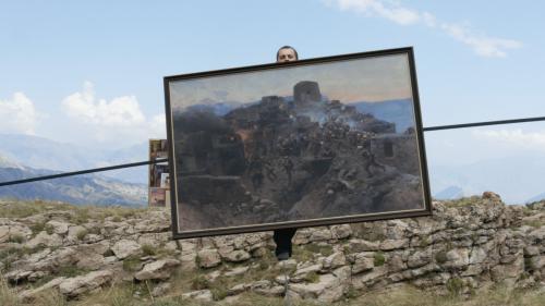 A still from Taus Makhacheva's video work Tightrope. It features the Russian tightrope walker Rasul Abakarov walking across a tightrope on the mountainside with a painting in his hands