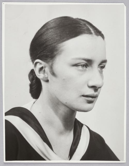 A young woman with her hair in a sleek bun and a neutral facial expression. 