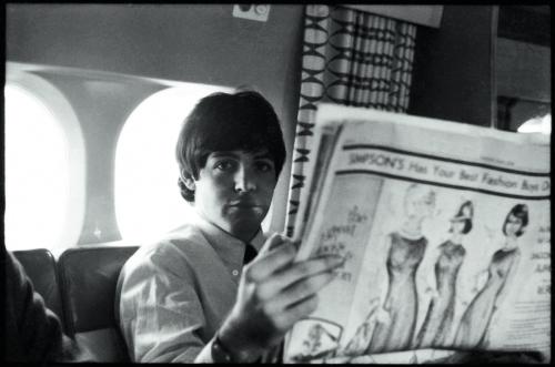 A photo of Paul McCartney on a plane reading the Toronto Star Newspaper in 1964